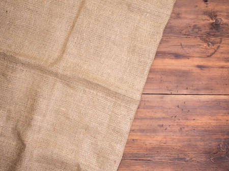 Old rural wooden table boards and burlap vintage background, photo top view. Hessian, sacking texture on wooden background for your design. Copy space for your message.の写真素材