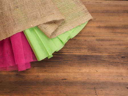 Creative, rustic background. The composition of burlap, crinkled green paper and a red grid on a brown background from old wood, rural table. Mock-up for your greetings card, poster or designの写真素材