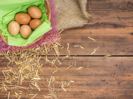 Rural eco background with brown chicken eggs, a piece of burlap and straw on the background of old wooden planks. The view from the top. Creative background for Easter cards or menuの写真素材