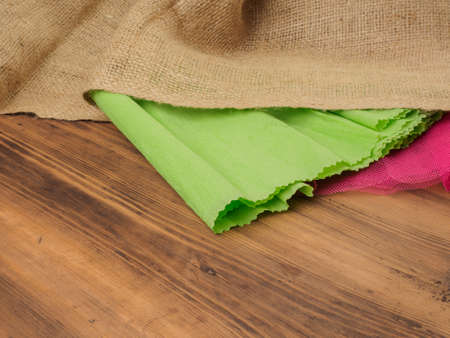 Creative, rustic background. The composition of burlap, crinkled green paper and a red grid on a brown background from old wood, rural table. Mock-up for your greetings card, poster or designの写真素材