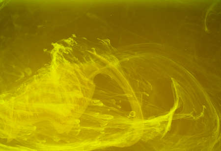 Abstract colored background. Yellow smoke, ink in water, the patterns of the universe. Abstract movement, frozen multicolor flow of paint. Horizontal photo with soft focus, blurred backdrop.の写真素材