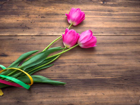Pink tulips, floral arrangement on wooden background from old boards and a space for messages. Background for Mothers Day, 8 March and other greeting cards for lovely women. Soft focus, top view.の写真素材