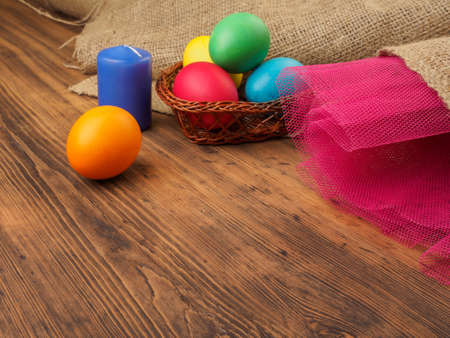 Easter colored egg with candle. Mock up for your greetings card or design. Russian and Ukrainian, orthodox, slavic traditional Easter, rural background with burlap and colored meshの写真素材