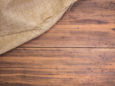 Old rural wooden table boards and burlap vintage background, photo top view. Hessian, sacking texture on wooden background for your design. Copy space for your message.の写真素材