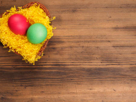 Colored chicken egg on background of bright yellow straw and old wooden table. The view from the top. Creative background for greeting cards, menu or advertisingの写真素材