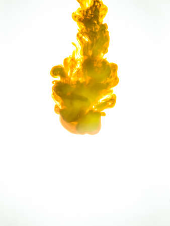 Ink swirl in water isolated on white background. The paint in the water. Soft dissemination a droplets of colored ink in water close-up. Abstract background. Explosion of splashes yellow acrylic ink.の写真素材