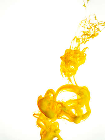 Ink swirl in water isolated on white background. The paint in the water. Soft dissemination a droplets of colored ink in water close-up. Abstract background. Explosion of splashes yellow acrylic ink.の写真素材