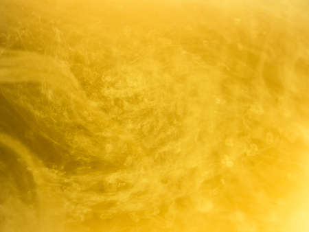Abstract colored background. Yellow smoke, ink in water, the patterns of the universe. Abstract movement, frozen multicolor flow of paint. Horizontal photo with soft focus, blurred backdrop.の写真素材