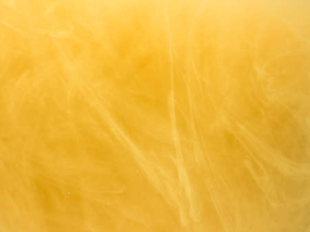Yellow smoke, ink in water. Abstract colored background. Frozen movement color flow of paint. Horizontal photo with soft focus, blurred backdrop.の写真素材