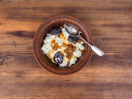 Curd in an earthenware bowl with the raisins, and dried apricots drizzled with honey on background of the table from the old boards. Illustration for blog articles or advertising.の写真素材