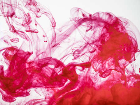 Process of dissolving acrylic ink into water. Amazing abstract background. Splash of colourful paint photographed while in motion. Acrylic cloud in liquid. Droplet of red color dissipation in liquidの写真素材