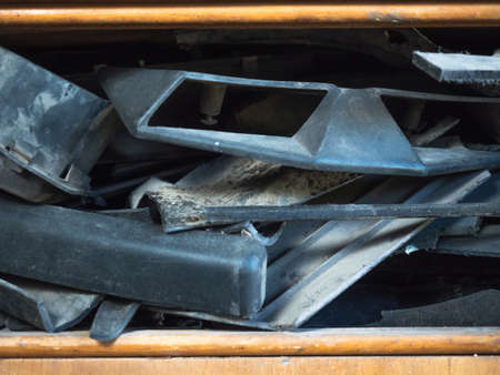 Close up view on dusty motor vehicle parts laying on brown shelf of wooden box. Different spare car parts background. Vintage wooden box in vehicle sprung. Dark dirty auto parts piled together in boxの写真素材