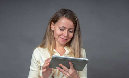 Portrait of european woman with tablet isolated on gray background. Smiling, cheerfully, joyfully...