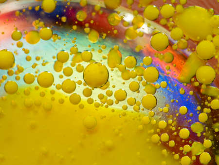 Scores of yellow paint drops on multicolour background. Close up macro shot. Blurred background....