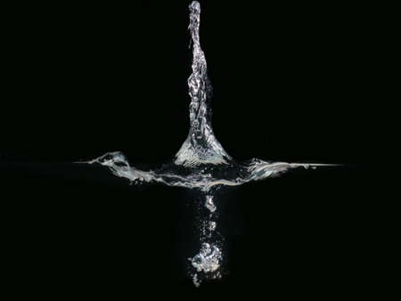 Droplet makes splash on water surface, isolated on black background. Bubbles underwater and rippling close up. Ready to use blending mode to screen or addの写真素材