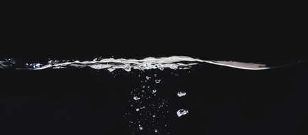 Waving liquid surface isolated on black background, close up view. Small water bubbles underwater. Black abstract background for overlays design, screen blending mode layerの写真素材