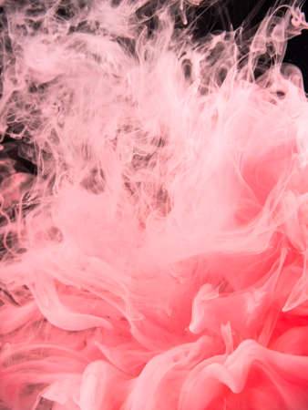 Pink-red acrylic smoke spreading under water, isolated on black background, close up view. Acrylic cloud dissolving into liquid. Abstract background for overlays design, screen blending mode layerの写真素材
