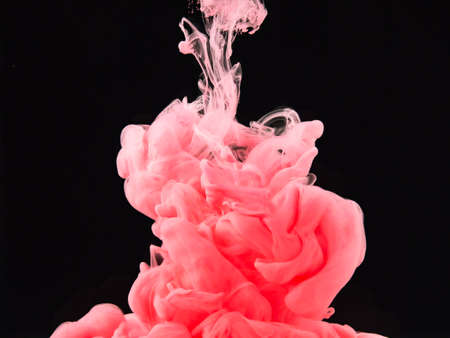 Pink ink dropped into water isolated on black background, close up view. Abstract swirl dissolving into liquid. Black background for overlays design, screen blending mode layerの写真素材