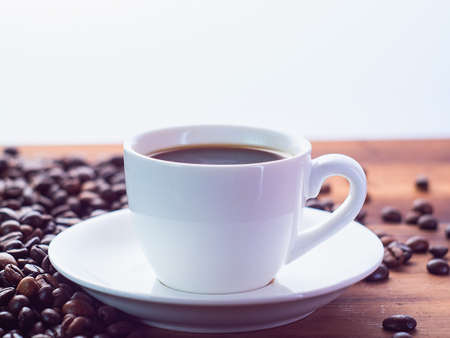 Background of white coffee cup with espresso on brown table, close up view. Roasted coffee beans...