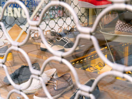 Barcelona, Spain - august 2019: wooden shelves with shoes, close up view. Window with white reja. Shoeshop in Barcelona, view from street. Selective soft focus. Blurred backgroundのeditorial素材