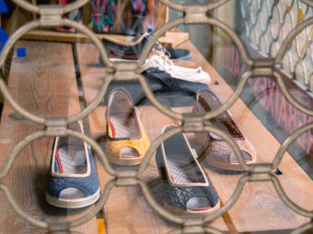 Barcelona, Spain - august 2019: shoes on wooden shelves, close up view. Shoeshop in Barcelona, view from street. Window with reja. Selective soft focus. Blurred backgroundのeditorial素材