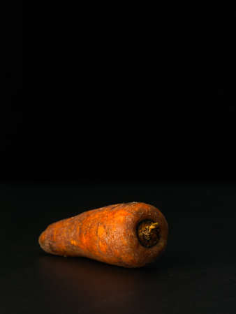 Raw carrot on black background close-up. Macro shoot. Low key photographic technique. Raw vegetablesの写真素材