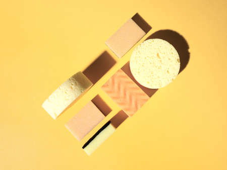 Geometric pattern with dishwashing sponges on orange background. Top down view. Abstract composition with copy space. Flat lay styleの写真素材