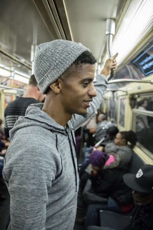 A tired, young african american man rides the NYC subway after a long day of work. Shot during the autumn of 2016.の写真素材
