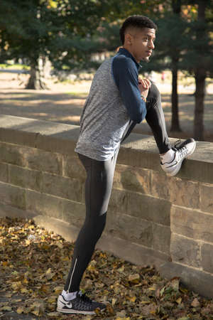 A young black man stretches to prepare for a run. Shot in Brooklyn, New York City during the Autumn of 2016.の写真素材