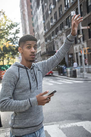A yoiung, African American man calls a cab in New York City. Shot during the autumn of 2016. Fully...