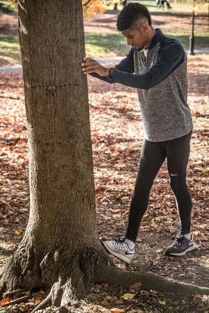 A young black man stretches to prepare for a run. Shot in Brooklyn, New York City during the Autumn of 2016.の写真素材
