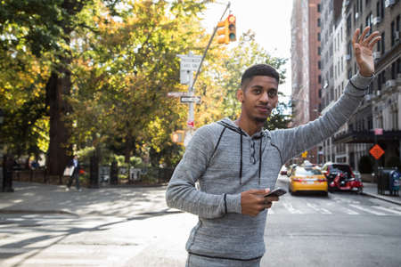 A yoiung, African American man calls a cab in New York City. Shot during the autumn of 2016. Fully released.の写真素材