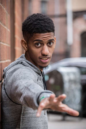 A young, hip, black man poses against a brick wall in NYC. Shot during the autumn of 2016 in New...