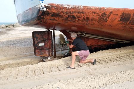 A shipyard worker loosens a rope from the ship's propellerのeditorial素材
