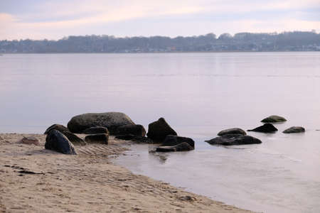 Boulders lie on the shore of a lakeの写真素材