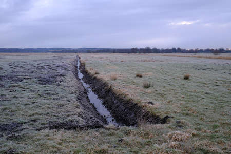 Freshly dug trench on a wet meadowの写真素材
