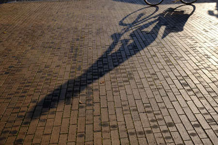 Silhouette of a bicycle on a sidewalkの写真素材