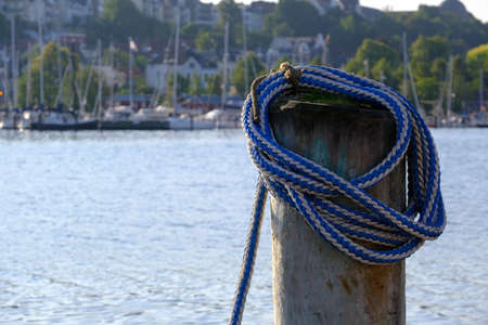 Coiled rope on a wooden bollard in the harborの写真素材