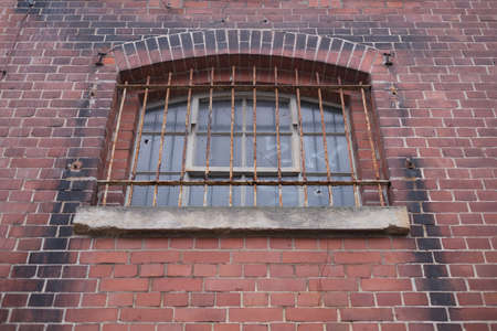 Old window with iron bars on the facade of an old brick buildingの写真素材