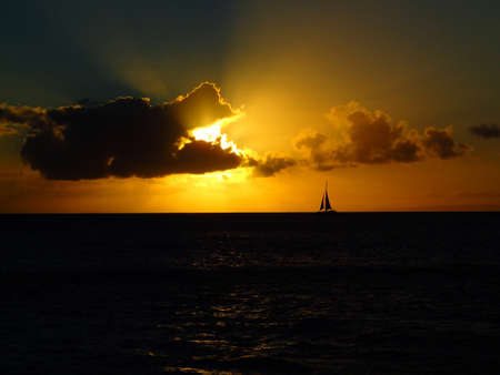 Sunset with Rays of Light and Silhouette of Sailboat on Horizonの写真素材