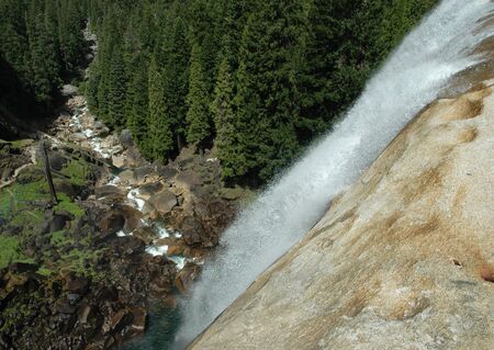 Aerial Shot of Waterfall Dropping into River Surrounded by Forest in California's Sierra Nevada Mountainsの写真素材