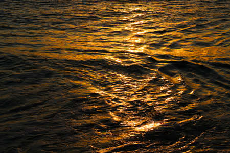 Close Up of Ocean Surface Glowing with Orange Sunset