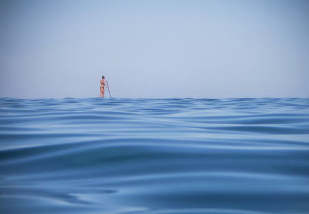 Woman Stand Up Paddle-Boards on Ocean Horizonの写真素材