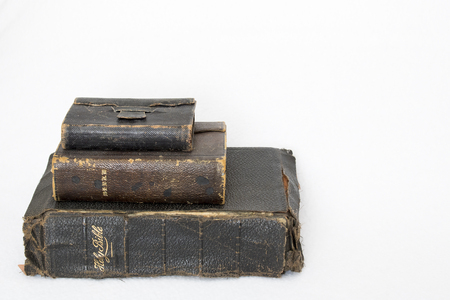 Three Antique Worn Leather Bibles on White Background