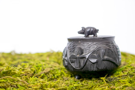 Close Up Small Hand Carved Antique Black Bog Oak Irish Pot with Pig Lid on Mossの写真素材