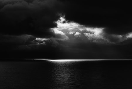 Light Breaks through Black Clouds over Dark Seaの写真素材