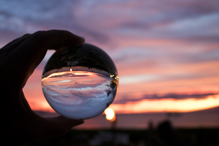 Bright Pink and Purple Sunset over Ocean Captured in Glass Ballの写真素材