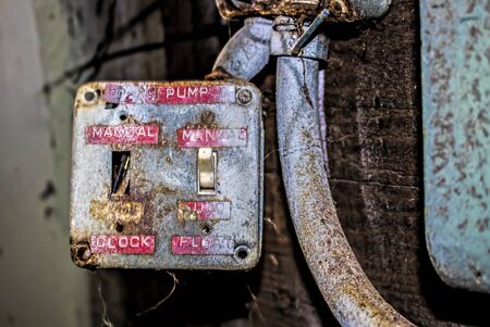 Old switches with red labels inside crumbling abandoned industrial cannery building in Monterey...