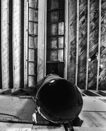 Lines textures and shapes in deteriorating wooden ceiling and metal pipes.  Black and white image of abandoned cannery warehouse in Monterey, California.の写真素材