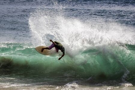 Man creates rooster tail skim boarding on wave at beach in Hawaii.の写真素材